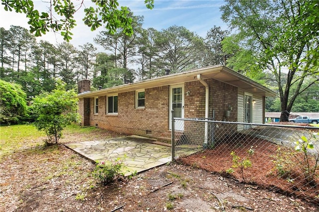 view of home's exterior with a patio, a chimney, crawl space, fence, and brick siding