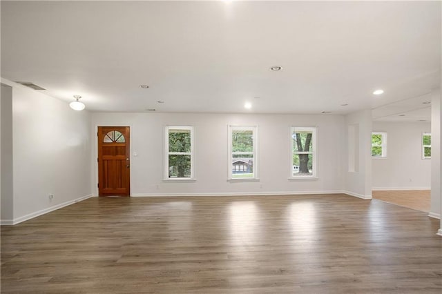 unfurnished living room with wood finished floors, recessed lighting, visible vents, and baseboards