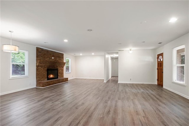 unfurnished living room featuring a fireplace, light wood finished floors, recessed lighting, and baseboards