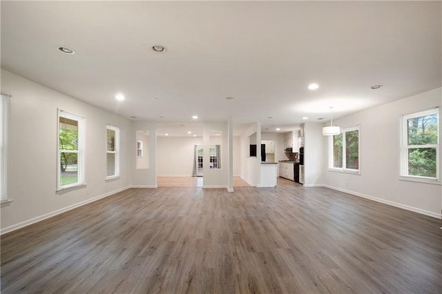 unfurnished living room with recessed lighting, light wood-style flooring, and baseboards