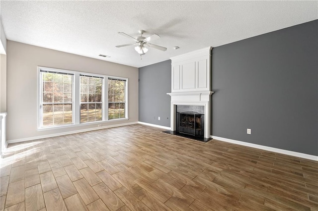 unfurnished living room with a textured ceiling, a large fireplace, and ceiling fan