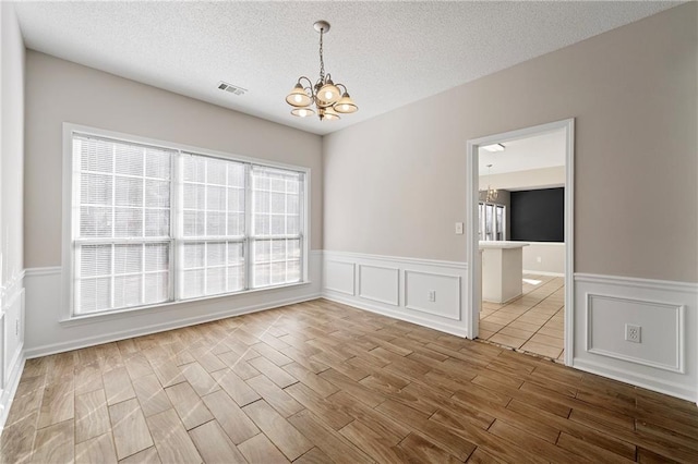 empty room with a chandelier and a textured ceiling