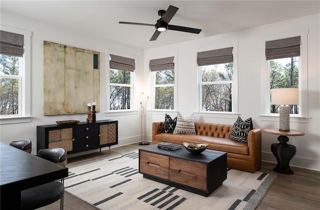 living area with wood finished floors, baseboards, and ceiling fan