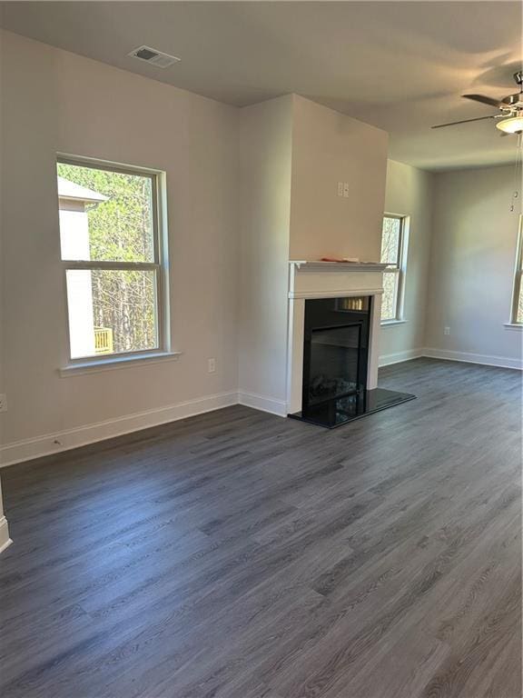 unfurnished living room with ceiling fan, dark hardwood / wood-style flooring, and a wealth of natural light