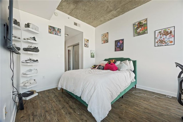 bedroom featuring a closet, wood finished floors, visible vents, and baseboards