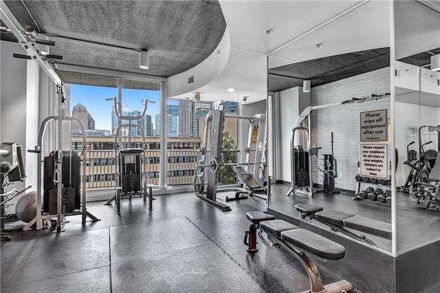 exercise room with floor to ceiling windows, a city view, and visible vents