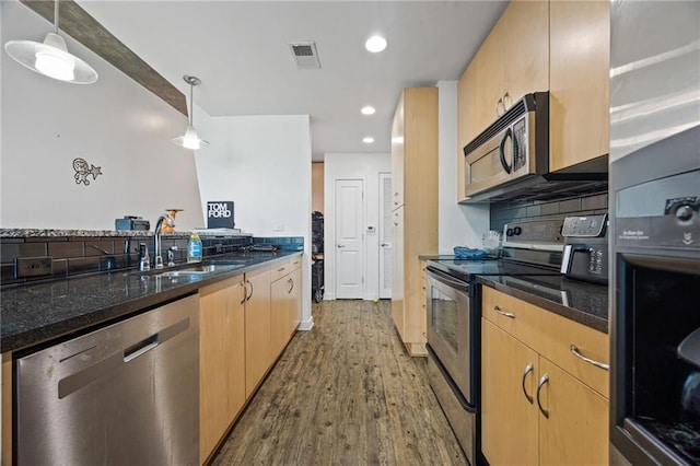 kitchen featuring dark stone counters, visible vents, wood finished floors, pendant lighting, and appliances with stainless steel finishes