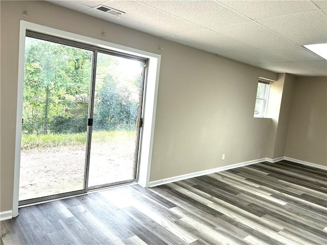 unfurnished room with dark hardwood / wood-style floors, a wealth of natural light, and a paneled ceiling