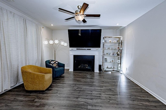 living room with a ceiling fan, a fireplace, baseboards, and wood finished floors