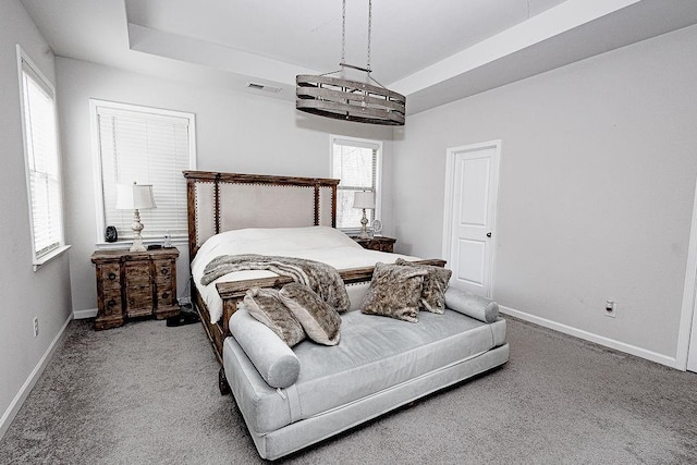 carpeted bedroom with a tray ceiling, visible vents, and baseboards