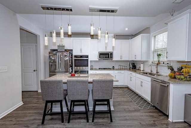 kitchen with stainless steel appliances, backsplash, dark wood-type flooring, white cabinetry, and a sink