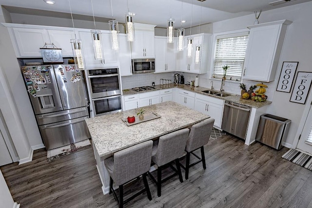 kitchen with dark wood-style flooring, a sink, white cabinets, appliances with stainless steel finishes, and tasteful backsplash