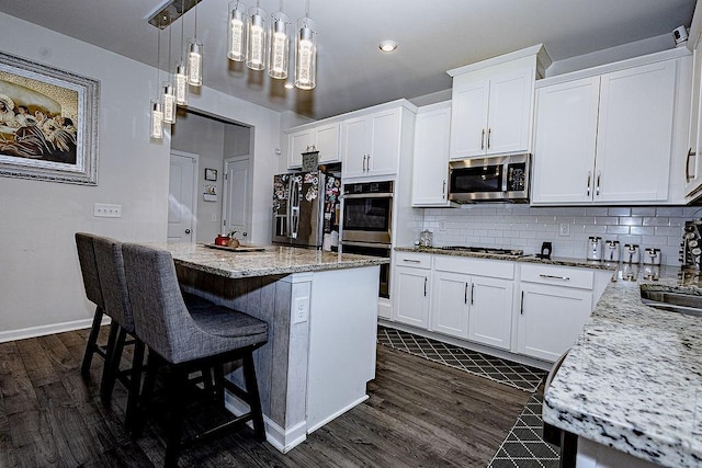 kitchen featuring stainless steel appliances, white cabinets, dark wood finished floors, and backsplash