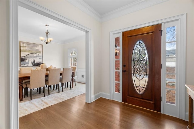 entryway with hardwood / wood-style flooring, ornamental molding, and a notable chandelier