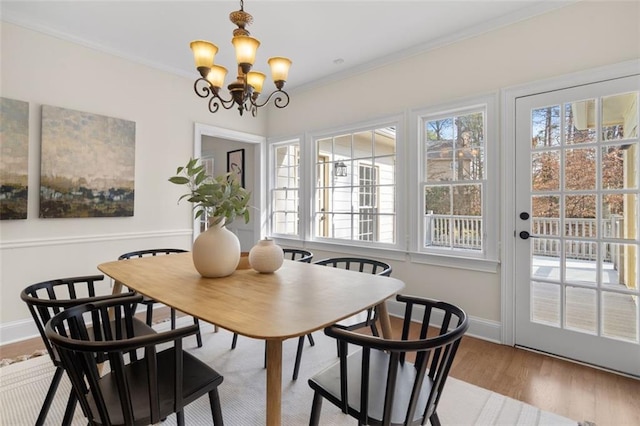 dining space with crown molding, plenty of natural light, a chandelier, and light wood-type flooring