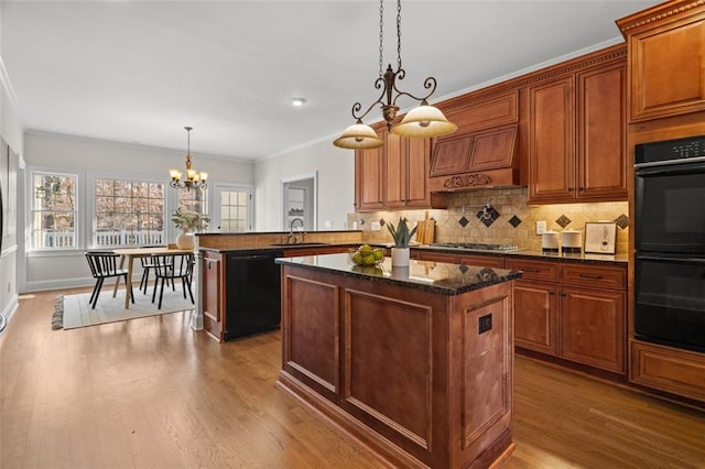 kitchen featuring sink, decorative light fixtures, kitchen peninsula, a kitchen island, and black appliances