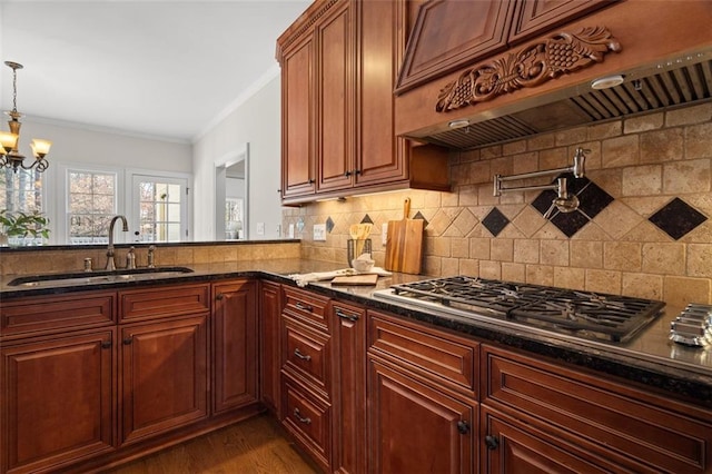 kitchen featuring sink, tasteful backsplash, hanging light fixtures, dark stone countertops, and custom range hood