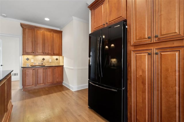 kitchen featuring crown molding, black refrigerator, backsplash, and light wood-type flooring