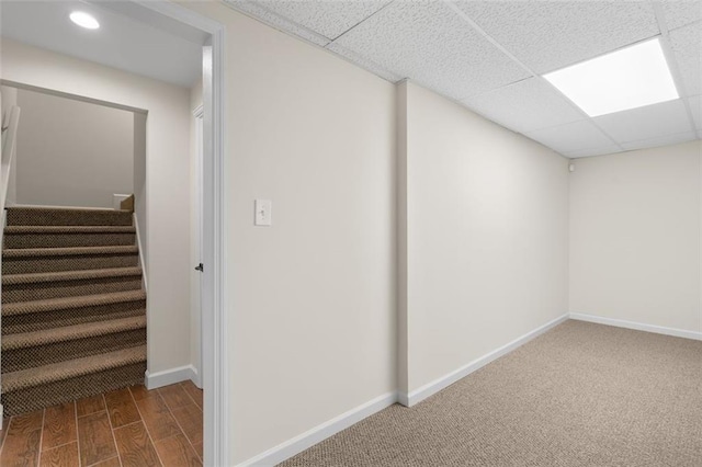 basement featuring a paneled ceiling and hardwood / wood-style floors