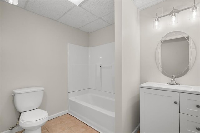 full bathroom with washtub / shower combination, vanity, a drop ceiling, tile patterned floors, and toilet