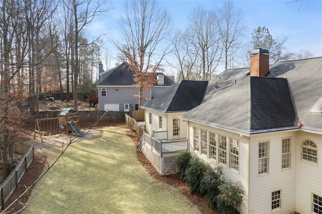 back of property featuring a yard, a playground, and a deck