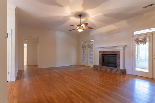 unfurnished living room featuring wood finished floors, a ceiling fan, ornamental molding, a fireplace, and baseboards