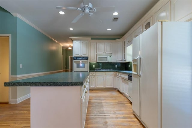 kitchen featuring white appliances, crown molding, a kitchen island, ceiling fan, and backsplash