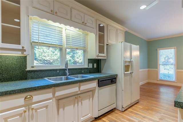 kitchen featuring white appliances, a sink, light wood-type flooring, dark countertops, and glass insert cabinets
