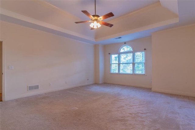unfurnished room with a tray ceiling, ceiling fan, carpet, and baseboards