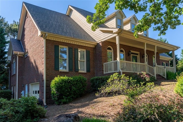 view of front of house with covered porch, brick siding, roof with shingles, and an attached garage