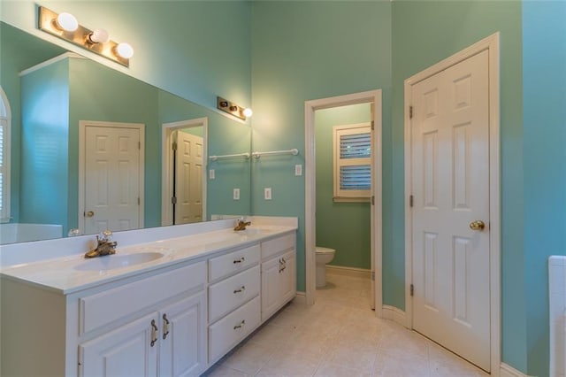 full bathroom featuring toilet, tile patterned flooring, baseboards, double vanity, and a towering ceiling