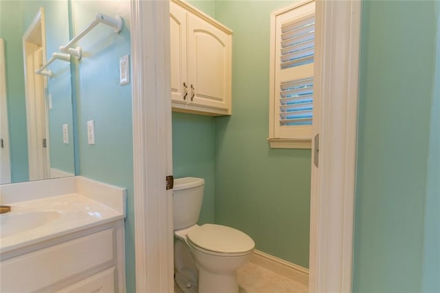 bathroom with toilet, vanity, baseboards, and tile patterned floors
