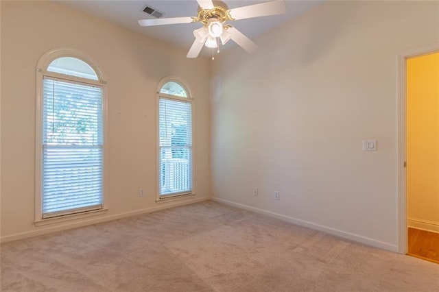 spare room featuring light carpet, baseboards, and a ceiling fan