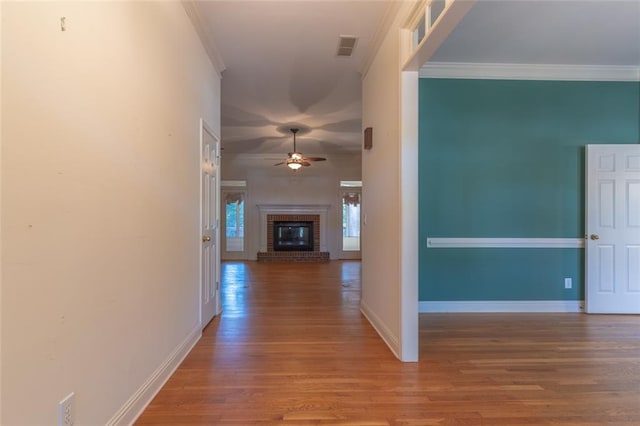 hallway featuring wood finished floors, crown molding, and baseboards
