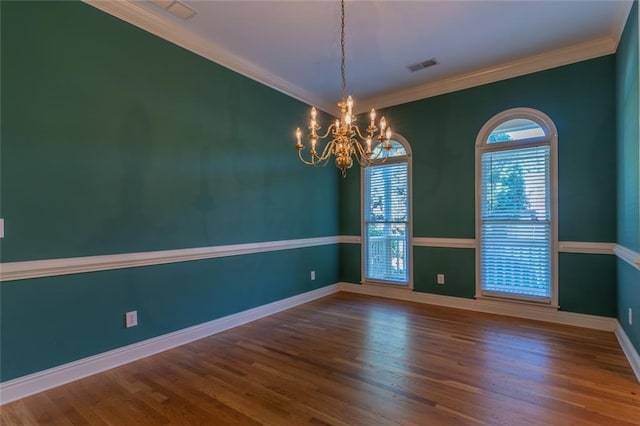 empty room featuring a chandelier, baseboards, wood finished floors, and ornamental molding