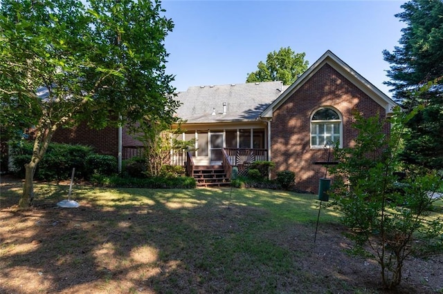 rear view of house with a sunroom, brick siding, and a lawn