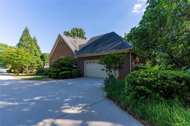 view of side of property featuring brick siding, driveway, and an attached garage