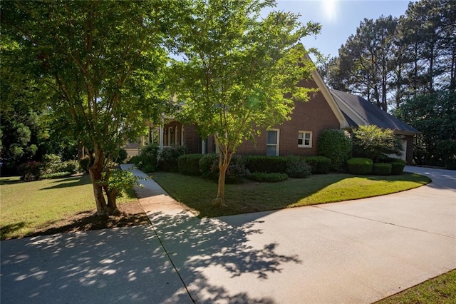 view of front facade featuring a front yard, brick siding, and driveway