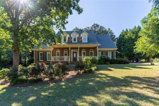 cape cod house featuring covered porch, a front lawn, and brick siding