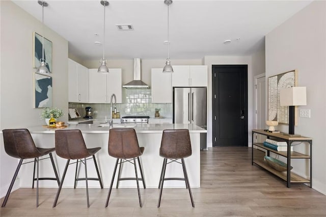 22 Airline St NE Unit 201, Atlanta, GA 30312 - kitchen featuring wall chimney range hood, a sink, tasteful backsplash, light countertops, and a breakfast bar