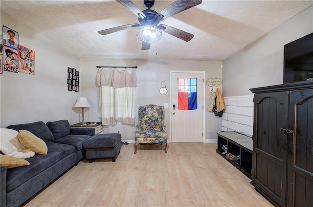 living room featuring a textured ceiling, light wood-style floors, and a ceiling fan