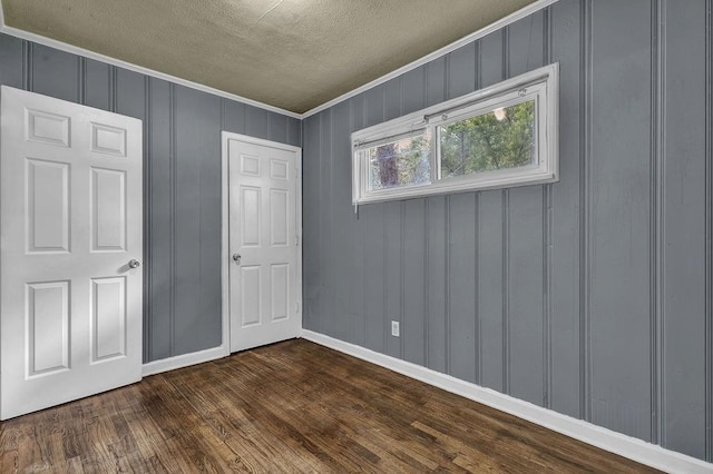 1911 Rosewood Rd, Decatur, GA 30032 - unfurnished bedroom with dark wood-style floors, a textured ceiling, ornamental molding, baseboards, and a decorative wall