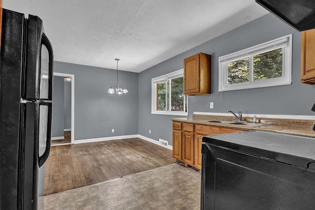 1911 Rosewood Rd, Decatur, GA 30032 - kitchen featuring black appliances, a sink, brown cabinetry, a chandelier, and baseboards