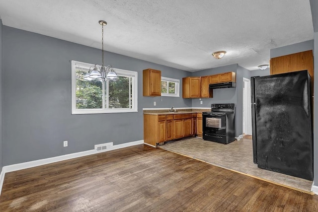 1911 Rosewood Rd, Decatur, GA 30032 - kitchen with black electric range, under cabinet range hood, wood finished floors, baseboards, and a textured ceiling