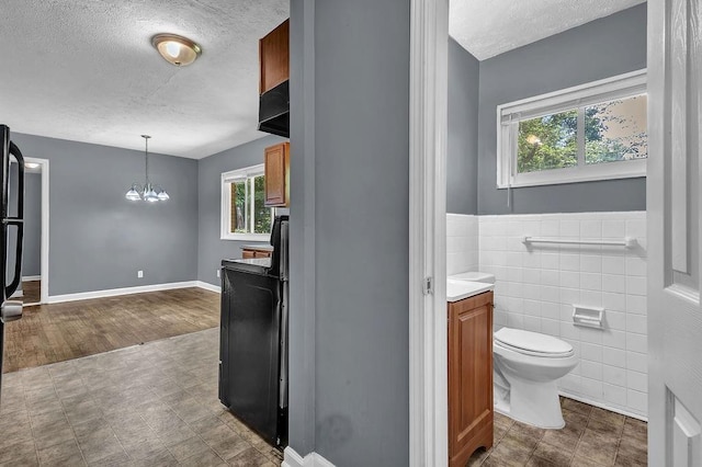 1911 Rosewood Rd, Decatur, GA 30032 - bathroom featuring a textured ceiling, tile walls, healthy amount of natural light, toilet, and vanity