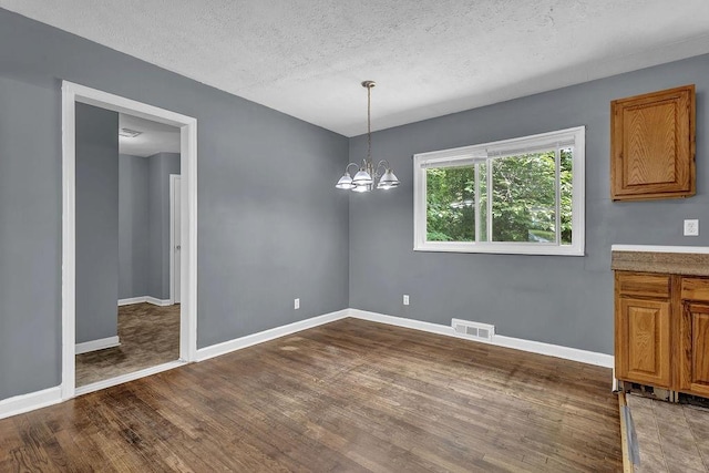 1911 Rosewood Rd, Decatur, GA 30032 - unfurnished dining area featuring dark wood-style flooring, baseboards, a chandelier, and a textured ceiling