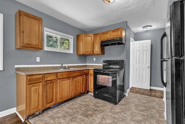 1911 Rosewood Rd, Decatur, GA 30032 - kitchen with black appliances, under cabinet range hood, a sink, a textured ceiling, and baseboards