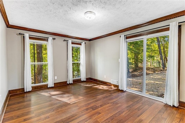 unfurnished room featuring dark hardwood / wood-style flooring, ornamental molding, and a textured ceiling