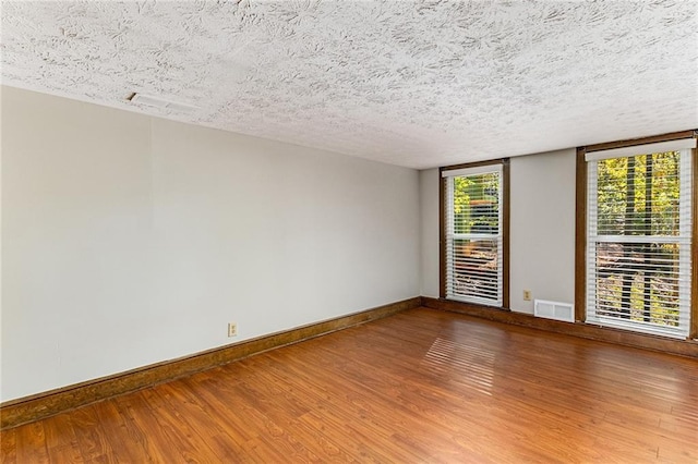 spare room featuring wood-type flooring and a textured ceiling