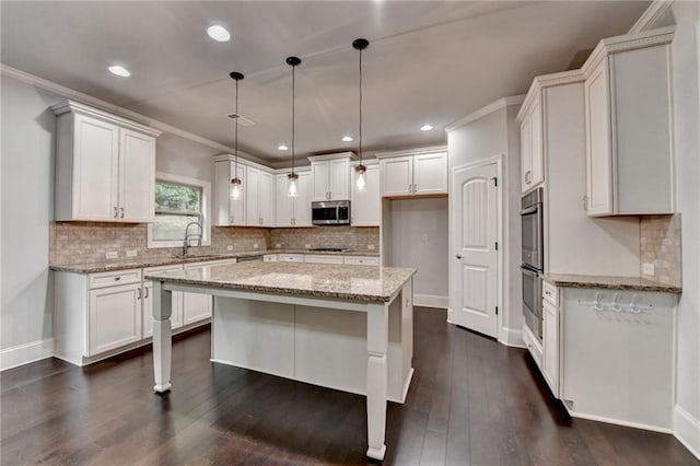 kitchen featuring light stone counters, a sink, stainless steel appliances, decorative backsplash, and a kitchen island